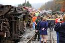 In this photo provided by the Pocahontas Times, crews work at the site where a truck carrying logs down Cheat Mountain on U.S. Route 250 crashed into the side of a train taking passengers on a scenic tour in rural Randolph County, W.Va., on Friday, Oct. 11, 2013. The crash killed one person and injured more than 60 others, according to emergency services officials. (AP Photo/The Pocahontas Times, Geoff Hamill)