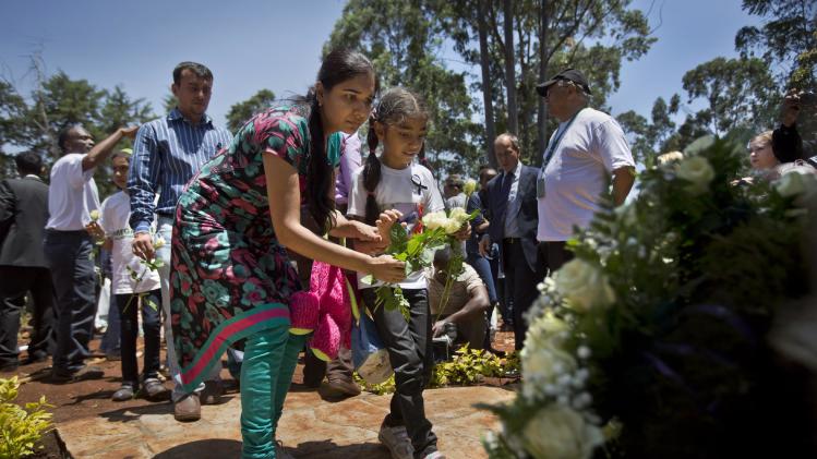 Relatives of those who died lay white roses at a stone memorial, during a memorial service marking the one-month anniversary of the the Sept. 21 Westgate Mall terrorist attack, in Karura Forest in Nairobi, Kenya Monday, Oct. 21, 2013. Families and friends of those killed in the attack planted trees in memory of lost loved ones in a ceremony that stressed that the attack occurred against people of all races and religions. (AP Photo/Ben Curtis)