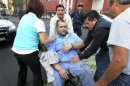 An injured man is being transported in an office chair outside the headquarters of state oil giant Pemex in Mexico City