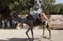 Men ride a camel past a polling station in Cairo