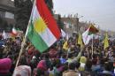 Kurdish civilians gather in the Syrian Kurdish city of Qamishli as they wave Kurdish flags in celebration