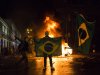 A demonstrator holds a Brazilian flag in front of a burning barricade during a protest in Rio de Janeiro in Rio de Janeiro, Brazil, Monday, June 17, 2013. Protesters massed in at least seven Brazilian cities Monday for another round of demonstrations voicing disgruntlement about life in the country, raising questions about security during big events like the current Confederations Cup and a papal visit next month. (AP Photo/Felipe Dana)