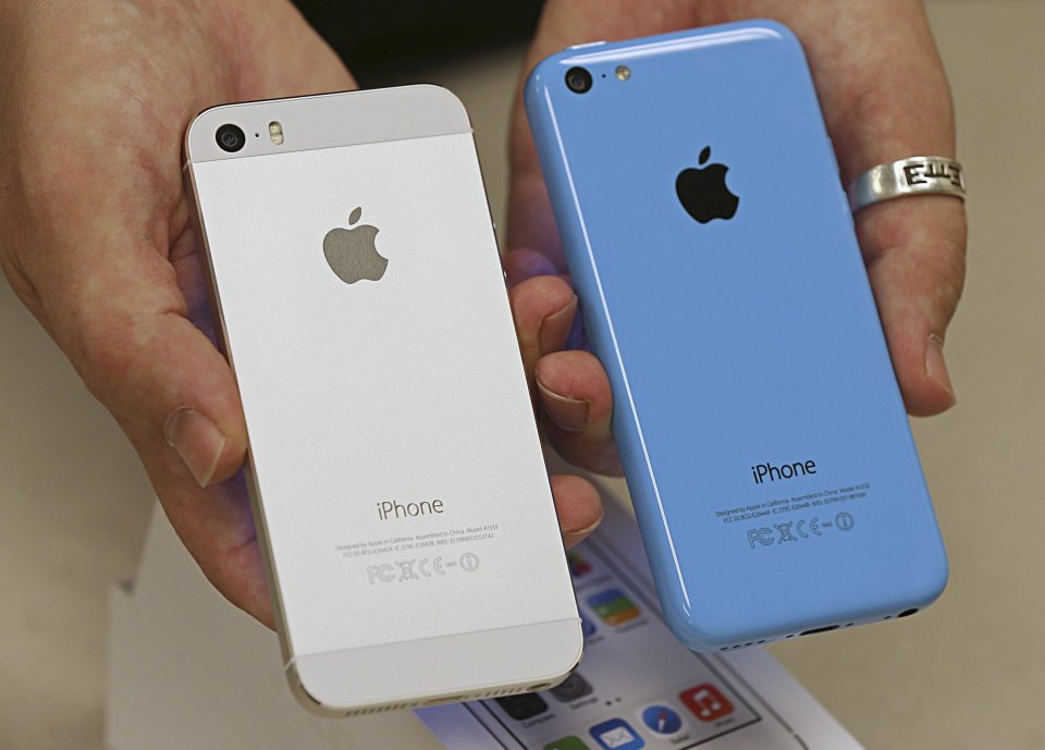 An employee shows the backside of a new Apple iPhone 5c and iPhone 5s at a Verizon store in Orem, Utah.
