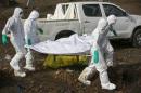 Health workers carry the body of a suspected Ebola victim for burial at a cemetery in Freetown
