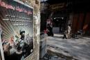 Syrians walk past a poster advertising the Syrian army in the old part of the capital Damascus on January 16, 2014