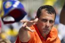 Opposition candidate Capriles throws his cap to supporters during an election rally in Caracas