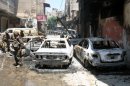 In this photo taken during a government-organized tour, Syrian soldiers stand next to burned cars after they regained control of the district of Midan, in the southern part of Damascus, Syria, Friday, July 20, 2012. Syrian troops and tanks on Friday drove rebels from a Damascus neighborhood where some of the heaviest of this week's fighting in the capital left cars gutted and fighters' bodies in the streets. Hundreds of people were killed in a single day, activists said, as the military struggles to regain momentum after a stunning bombing against the regime's leadership. (AP Photo/Bassem Tellawi)