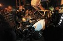 People look at the wreckage of a police car after an attack, in Benghazi
