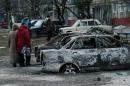 People look at burned out cars as they walk along a street in the southern Ukrainian city of Mariupol on January 25, 2015 a day after a rocket barrage blamed on Kremlin-backed Ukrainian rebels killed 30 in the city