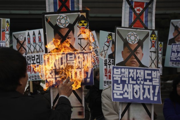 An activist from an anti-North Korea civic group burns a portrait of North's leader Kim Jong-un during a rally against North Korea's nuclear test near the U.S. embassy in central Seoul February 12, 2013. North Korea conducted its third nuclear test on Tuesday in defiance of U.N. resolutions, angering the United States and Japan and prompting its only major ally, China, to call for calm. The poster (front R) reads, "Let's pulverize North Korea's nuclear war provocations!"  REUTERS/Kim Hong-Ji (SOUTH KOREA - Tags: CIVIL UNREST POLITICS TPX IMAGES OF THE DAY)
