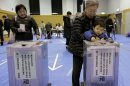 A boy places his grandmother's vote into a ballot box at a polling station in Tokyo, Sunday, Dec. 16, 2012. Voters cast their ballots Sunday in parliamentary elections which are likely to hand power back to a conservative party that ruled Japan for most of the post-war era. (AP Photo/Itsuo Inouye)