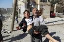 A Syrian man carries a wounded child following a reported air strike attack by government forces on the outskirts of the northern city of Aleppo on February 14, 2014