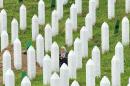 A Bosnian Muslim woman, survivor of the Srebrenica 1995 massacre, searches for remains of her relative at a memorial cemetery in the village of Potocarion near Srebrenica, on July 10, 2014