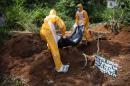 A team of funeral agents specialised in the burial of victims of the Ebola virus put a body in a grave at the Fing Tom cemetery in Freetown, on October 10, 2014