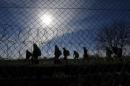 Migrants walk along Hungary's border fence on the Serbian side of the border near Morahalom