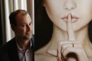 Ashley Madison founder Noel Biderman poses with a poster during an interview in Hong Kong