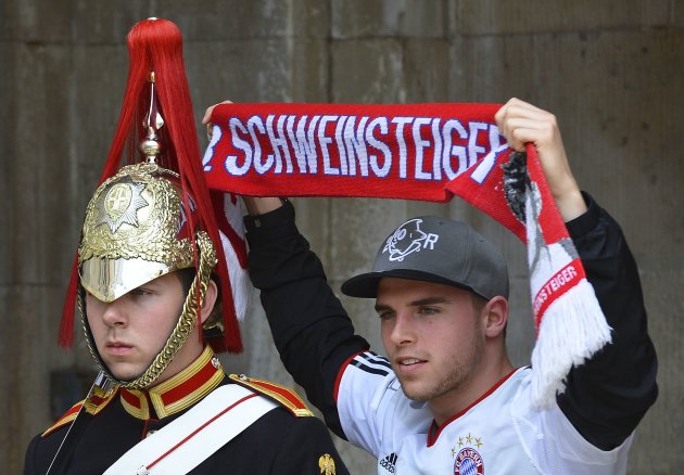 A Bayern Munich supporter poses next to a member of The Queen's Life Guard standing on duty outside of Horse Guards in central London