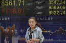A woman walks in front of the electronic stock board of a securities firm showing Japan's Nikkei 225 index gained 118.61 points to 8561.71 in Tokyo, Friday, July 27, 2012. Asian stocks charged higher Friday after the European Central Bank's chief vowed to save the euro currency union from the continent's debt crisis and Samsung Electronics reported another record quarterly profit. (AP Photo/Itsuo Inouye)