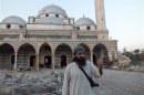 A Free Syrian Army fighter gestures in front of the damaged Khalid bin al Walid Mosque in Homs