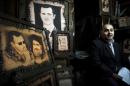 FILE -- In this Feb. 24, 2016 file photo, a Syrian shopkeeper waits for customers next to paintings of of President Bashar Assad, and Hezbollah leader Sheikh Hassan Nasrallah, center, at the Souk Tawil market in Damascus, Syria. Turkey said Thursday, Dec. 29, 2016, that Lebanon's militant Hezbollah group, which has sent thousands of fighters to support President Bashar Assad, should withdraw from Syria. In an interview with Turkey's A Haber news channel, Foreign Minister Mevlut Cavusoglu also said Turkey and Russia are close to reaching an agreement on a nationwide Syrian cease-fire that would come into effect by the end of the year. (AP Photo/Hassan Ammar, File)