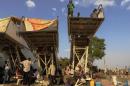 South Sudanese men shelter under disused mobile staircases as young children play at a makeshift IDP camp at the UNMISS compound in Juba on December 22, 2013