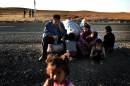 Kurdish refugees who evacuated the Syrian town of Ain al-Arab, known as Kobane by the Kurds, sit on the side of the road after crossing the border into Turkey at the town of Suruc on October 5, 2014