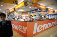 A security guard walks past a Lenovo shop in a computer mall in Beijing on November 3, 2011. Lenovo on Sunday unveiled a home tabletop touch-screen computer aimed at turning typically solitary online activities into family affairs