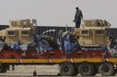 A driver stands on top of a truck carrying NATO Humvees at a terminal in the Pakistani-Afghan border, in Chaman, Pakistan, Wednesday, July 4, 2012. Trucks carrying NATO troop supplies are set to resume shipments to Afghanistan on Wednesday following a deal between the U.S. and Pakistan that ended Islamabad's seven-month blockade. (AP Photo/Matiullah Achakzai)