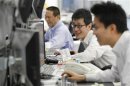 Foreign exchange dealers smile as they conduct trading at a dealing room in Tokyo