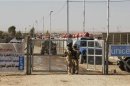Iraqi army soldiers stand guard at a gate refugee camp in al-Qaim