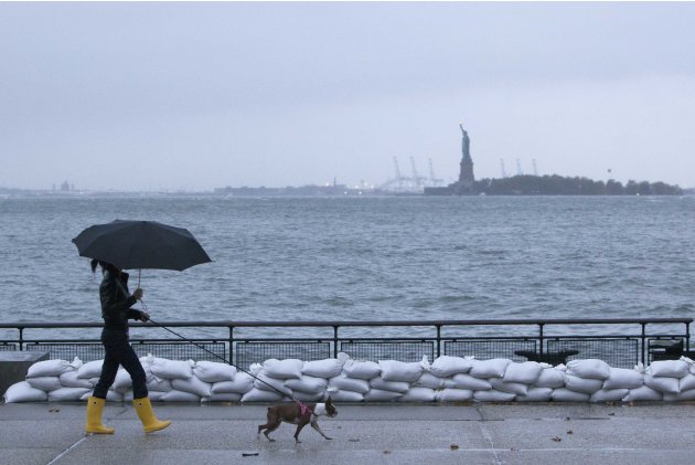 A woman walks her dog by sandbags in Battery Park in downtown Manhattan as Hurricane Sandy made its approach in New York