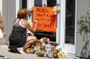 A woman writes on a sign outside Dr. Walter James Palmer's dental office in Bloomington, Minn., Wednesday, July 29, 2015. Palmer reportedly paid $50,000 to track and kill a black-maned lion, just outside Hwange National Park in Zimbabwe. (AP Photo/Ann Heisenfelt)
