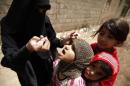 A health worker administers drops of polio vaccine to children in an outskirt of the Yemeni capital Sanaa