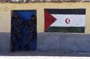 Security men stand next to a mural with the Western Sahara flag at the Smara refugee camp in Algeria's Tindouf province on on February 22, 2016
