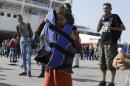 A girl covers her face to protect from the sun with a life jacket after her arrival from the northeastern Greek island of Lesbos at the Athens port of Piraeus Friday, Sept. 4, 2015. About 2,500 people arrived on the ferry Eleftherios Venizelos. The Greek Government does not see an end to the flood of refugees and migrants anytime soon with the vast majority of migrants reaching five eastern Greek islands, with Lesbos seeing 50 percent of the arrivals. (AP Photo/Thanassis Stavrakis)