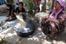 Kurdish women bake bread on a domed metal griddle for baking traditional flat bread, known locally in the region as the saj, at the mosque where they sought refuge in the village of Hajyawa, Iraq's Sulaimaniyah district, on August 21, 2014