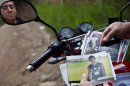 CORRECTS LAST NAME SPELLING AND ADDS FIRST NAME 'EBED' - In this Oct 17, 2012 photo, Wilfredo Yanes, reflected on a mirror of his motorcycle, shows pictures of his late son Ebed Jaasiel Yanes, 15, at the site where he was shot dead allegedly by soldiers in Tegucigalpa, Honduras. According to his relatives, Yanes was killed by soldiers early Sunday, May 27, when he was riding a motorcycle, near a military checkpoint. (AP Photo/Esteban Felix)