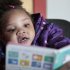 In this photo taken Dec. 8, 2011, Taliyah Garrett, 3, looks at a book as she gets help in learning to read by a coordinator from the Parent Child Home Program during a visit in Seattle. The home visiting program, supported by United Way of King County, Wash., helps children from low-income families prepare for kindergarten by tutoring parents in how to teach their children. As the first signs of an economic recovery make the news, many of the nation's nonprofit organizations are digging in for another three to four years of financial distress, according to researchers who keep an eye on the chartable world. (AP Photo/Elaine Thompson)