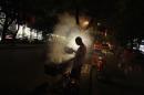 A man fans a grill while cooking kebabs at a roadside stall, in central Beijing