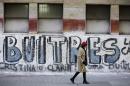A woman walks by a graffiti that reads in Spanish "Vultures," in reference to the dispute between the Argentine government and a U.S. hedge fund, known locally as "vulture funds," in Buenos Aires, Argentina, Monday, August 4, 2014. The full graffiti reads "out vultures." The collapse of talks with U.S. creditors sent Argentina into its second debt default in 13 years and raised questions about what comes next for financial markets and the South American nation's staggering economy. (AP Photo/Victor R. Caivano)