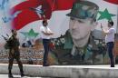 A man takes a photo of his friend in front of a poster of Syria's President Bashar al-Assad at Umayyad Square in Damascus