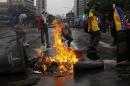 A small group of anti-government protesters block an avenue with a burning barricade after a march in Caracas