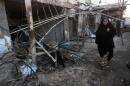 An Iraqi woman walks near debris on February 18, 2014, a day after an explosion in the Ur district in eastern Baghdad