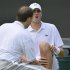 John Isner of the U.S. reacts as a trainer attends to his injured knee, before he retired from his men's singles tennis match against Adrian Mannarino of France at the Wimbledon Tennis Championships, in London