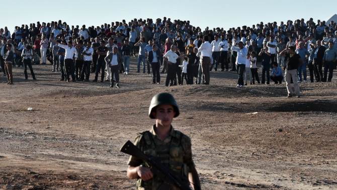 Kurdish protesters gather on a hill opposite the Syrian town of Ain al-Arab, known as Kobane by the Kurds, on the Turkish border with Syria near the city of Sanliurfa on October 4, 2014