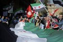Demonstrators wave Syrian National Coalition flags as they rally against Bashar al-Assad in Rome on April 13, 2013