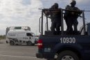 Federal police on a vehicle guard one of the three forensic trucks where several bodies were placed after dozens of bodies, some of them mutilated, were found on a highway connecting the northern Mexican metropolis of Monterrey to the U.S. border found in the Km 47 of the Reynosa-Cadereyta road in the town of San Juan near the city of Monterrey, Mexico, Sunday, May 13, 2012. (AP Photo/Christian Palma)