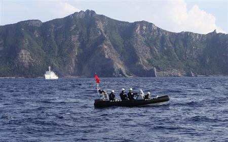 A Japan Coast Guard boat (front) and vessel sail as Uotsuri island, one of the disputed islands, called Senkaku in Japan and Diaoyu in China, is pictured in the background, in the East China Sea August 18, 2013. REUTERS/Ruairidh Villar/Files