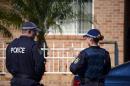 Police officers stand guard outside a house during a raid in the Guildford area of Sydney on September 18, 2014