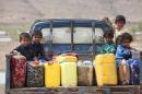 Children ride on the back of a truck loaded with water jerrycans at a camp for internally displaced people in the Dhanah area of the central province of Marib, Yemen